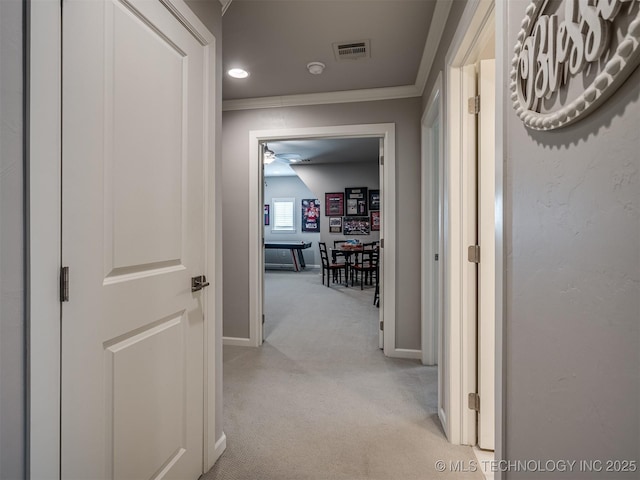 hall with crown molding, baseboards, light colored carpet, and visible vents