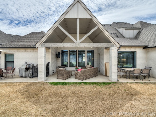 back of house with an outdoor hangout area, a patio, brick siding, and roof with shingles