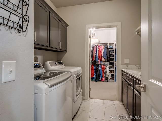 clothes washing area with cabinet space, marble finish floor, and washer and dryer