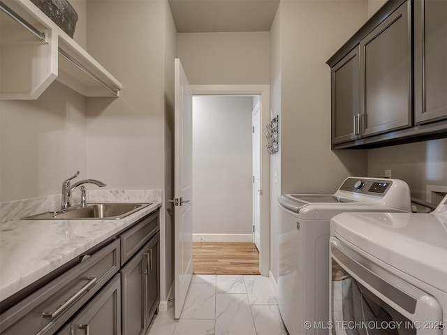 laundry room with a sink, marble finish floor, baseboards, washer and dryer, and cabinet space