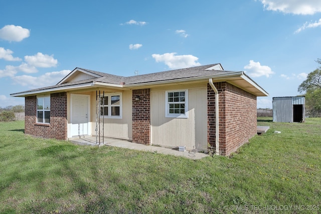 back of house with a lawn, brick siding, and a shingled roof