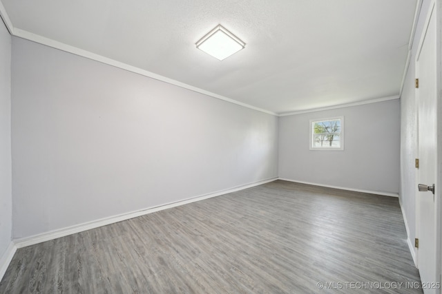 unfurnished room featuring ornamental molding, baseboards, and wood finished floors