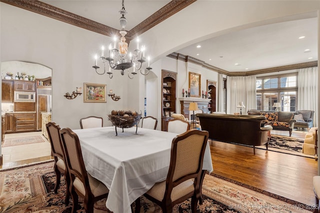 dining room with light wood-style flooring, arched walkways, recessed lighting, a notable chandelier, and ornamental molding