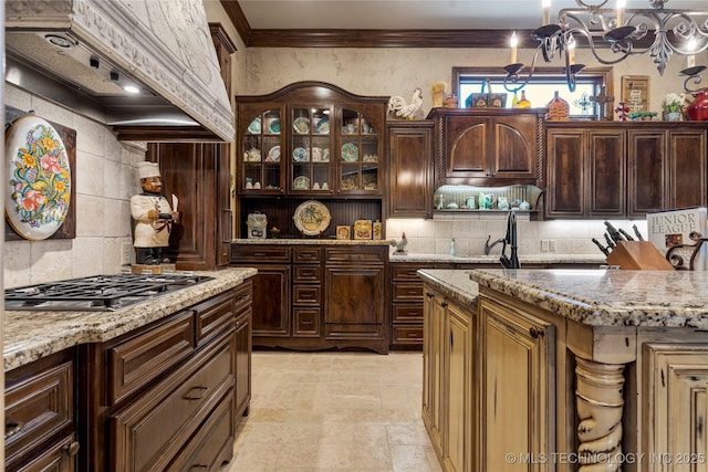 kitchen with stainless steel gas cooktop, an inviting chandelier, custom exhaust hood, and tasteful backsplash