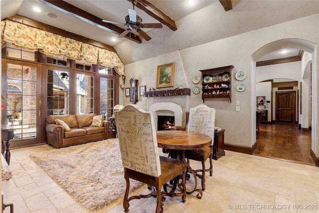 dining space with stone tile floors, ceiling fan, arched walkways, baseboards, and beam ceiling