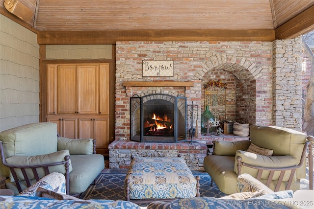 living area with wood walls, wooden ceiling, and a brick fireplace