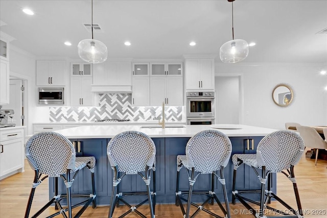 12202 S 102 E Ave, Bixby, OK 74008 - kitchen with light countertops, visible vents, stainless steel appliances, an island with sink, and custom range hood