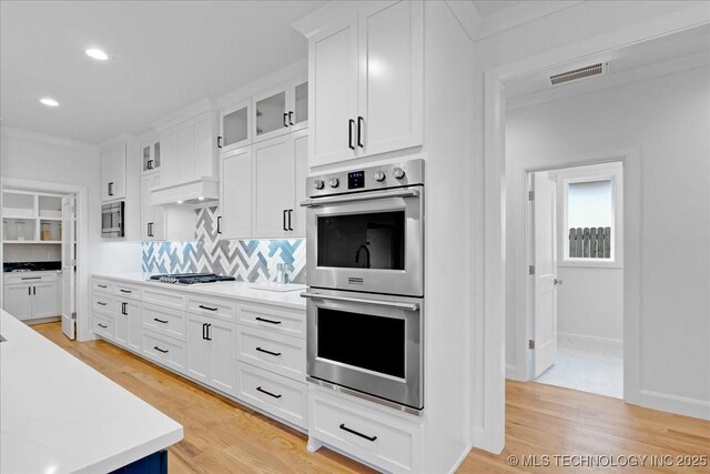 12202 S 102 E Ave, Bixby, OK 74008 - kitchen featuring glass insert cabinets, white cabinets, light wood-style floors, and appliances with stainless steel finishes