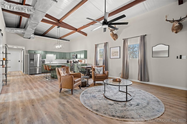 living area featuring baseboards, a high ceiling, beam ceiling, light wood-style floors, and ceiling fan