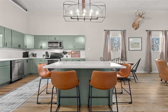 kitchen with green cabinetry, light countertops, light wood-style floors, and appliances with stainless steel finishes
