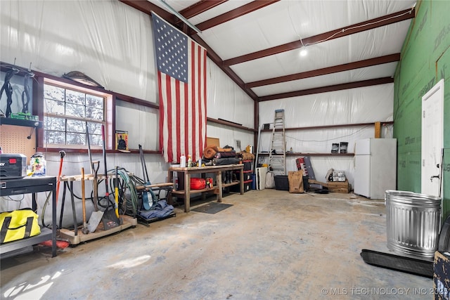 garage featuring freestanding refrigerator, a workshop area, and metal wall