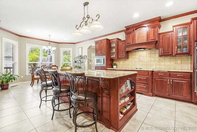 11748 S Canton Ave, Tulsa, OK 74137 - kitchen with stainless steel microwave, light tile patterned floors, a kitchen island with sink, and an inviting chandelier