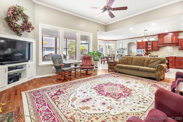 11748 S Canton Ave, Tulsa, OK 74137 - living room featuring crown molding, light wood-type flooring, baseboards, arched walkways, and ceiling fan
