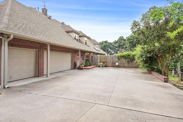 11748 S Canton Ave, Tulsa, OK 74137 - view of side of home with driveway, roof with shingles, an attached garage, fence, and brick siding