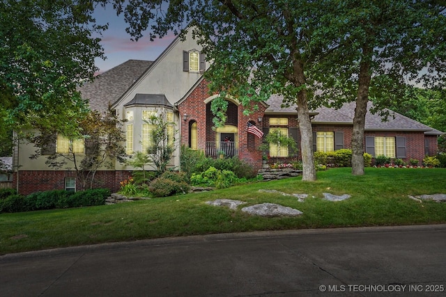 11748 S Canton Ave, Tulsa, OK 74137 - tudor home featuring a shingled roof, a lawn, stucco siding, and brick siding