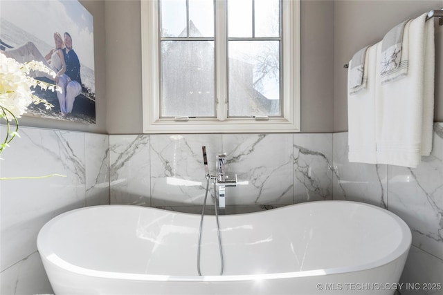 bathroom with a soaking tub and tile walls