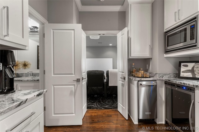 kitchen featuring ornamental molding, dark wood-style floors, stainless steel microwave, white cabinetry, and light stone counters
