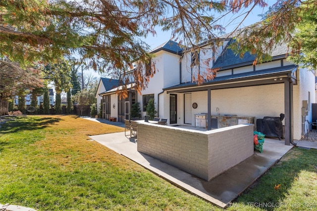 rear view of property featuring a yard, a patio area, and brick siding