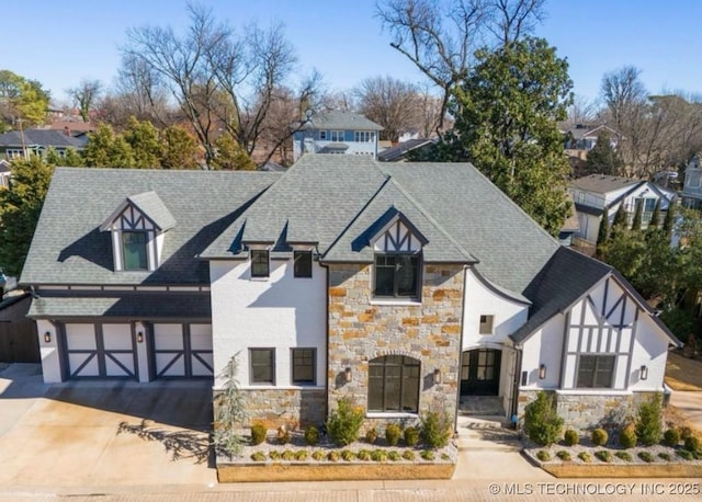 view of front of home featuring a shingled roof, driveway, a garage, and stone siding