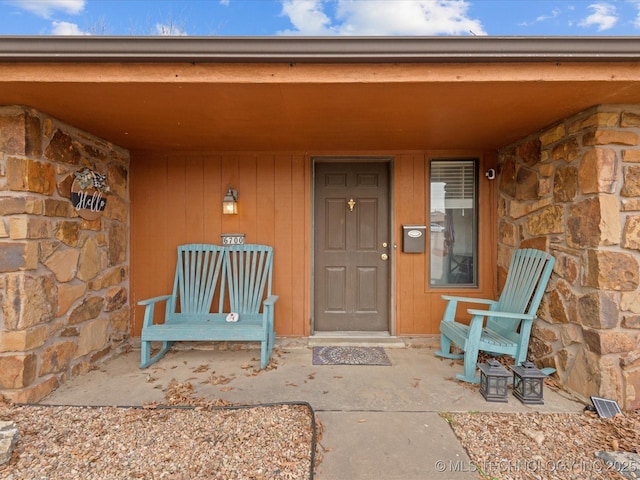view of exterior entry with a porch and stone siding