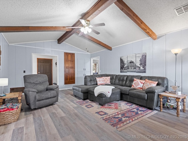 living area with visible vents, a ceiling fan, wood finished floors, and a textured ceiling