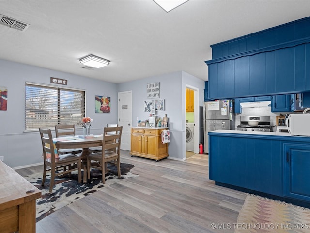 dining space featuring baseboards, light wood-style flooring, washer / clothes dryer, and visible vents