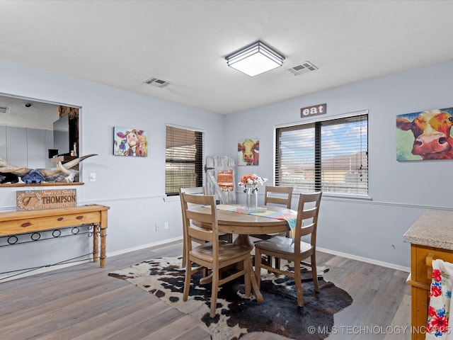 dining room featuring a wainscoted wall, visible vents, and wood finished floors