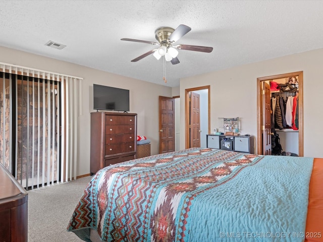 carpeted bedroom featuring visible vents, a ceiling fan, and a textured ceiling
