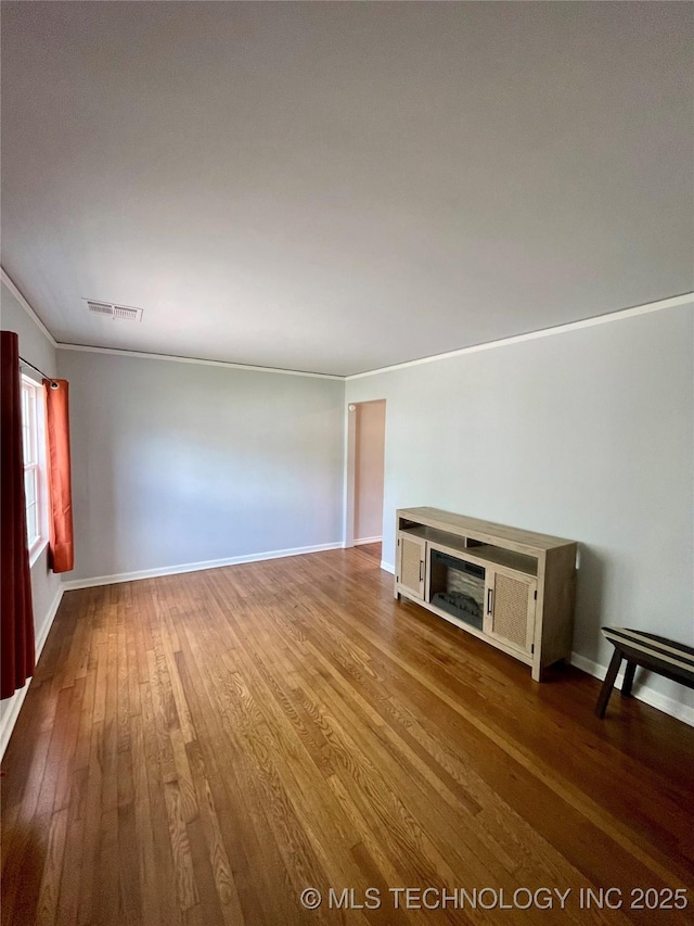 unfurnished living room featuring baseboards, visible vents, and dark wood-style flooring