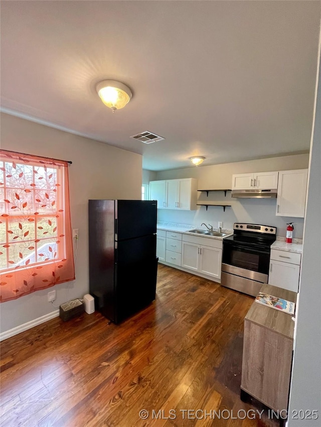 kitchen with a sink, freestanding refrigerator, stainless steel electric range, visible vents, and white cabinets