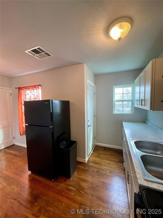 kitchen featuring dark wood-style flooring, light countertops, visible vents, and freestanding refrigerator