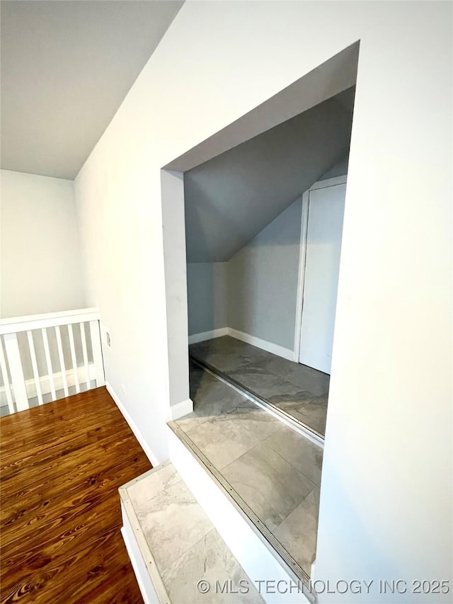 additional living space with baseboards, vaulted ceiling, and wood finished floors