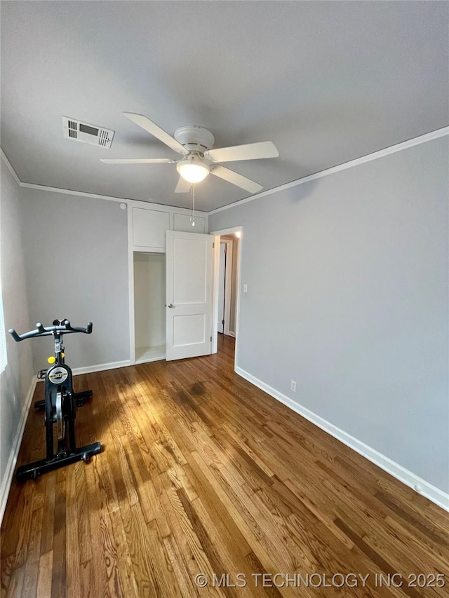 unfurnished bedroom featuring visible vents, baseboards, ornamental molding, wood finished floors, and a ceiling fan