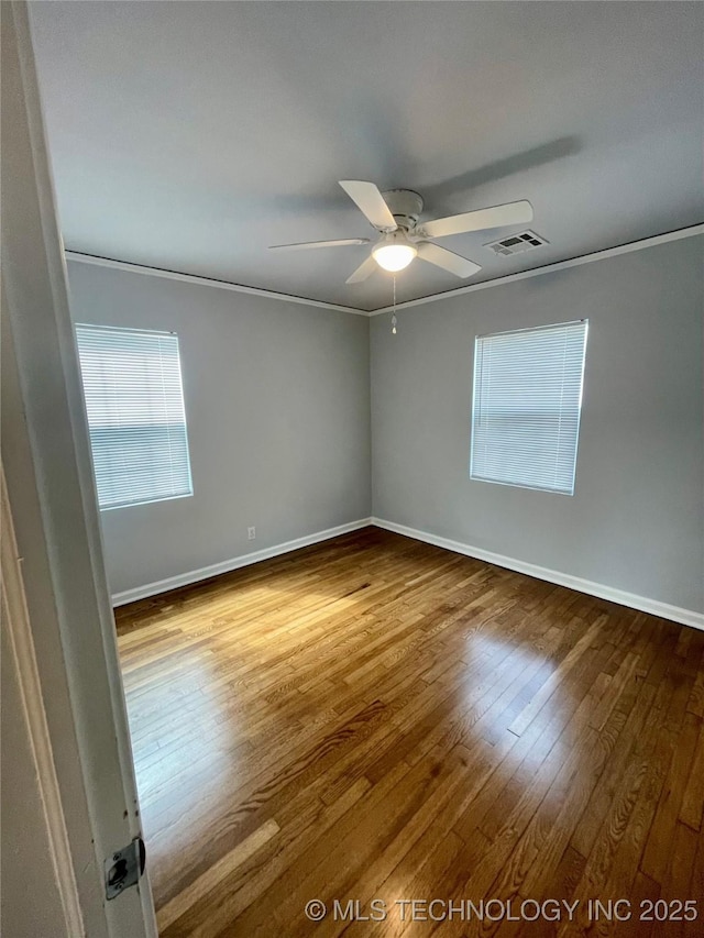 empty room with visible vents, baseboards, ornamental molding, wood finished floors, and a ceiling fan