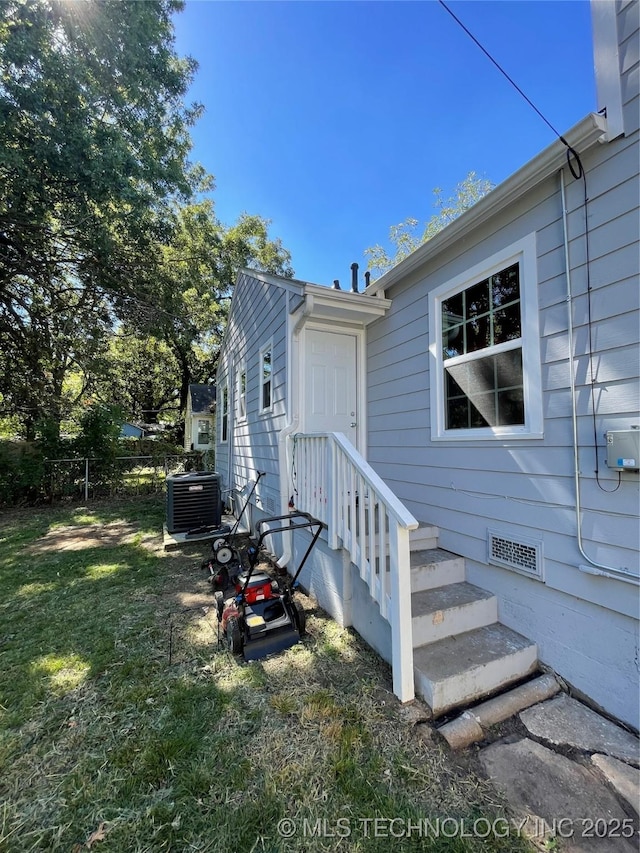 exterior space featuring central air condition unit, fence, and a yard