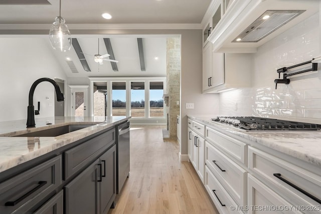 kitchen with a ceiling fan, premium range hood, appliances with stainless steel finishes, white cabinetry, and a sink