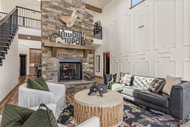 22450 S Rocky Ridge Ln, Claremore, OK 74019 - living room featuring a towering ceiling, wood finished floors, a stone fireplace, baseboards, and beamed ceiling