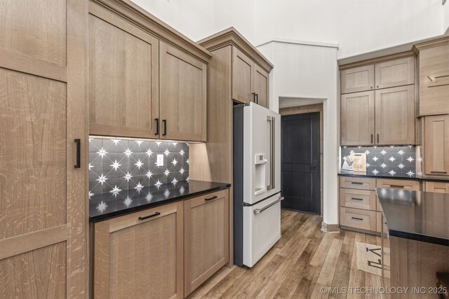 22450 S Rocky Ridge Ln, Claremore, OK 74019 - kitchen with white fridge with ice dispenser, dark countertops, decorative backsplash, and light wood finished floors