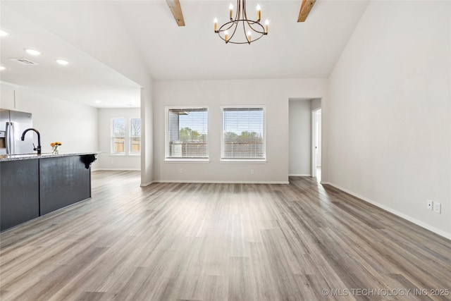13119 S 72nd E Pl, Bixby, OK 74008 - unfurnished living room with baseboards, light wood finished floors, high vaulted ceiling, and a notable chandelier