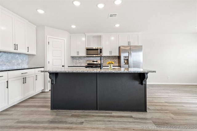 13119 S 72nd E Pl, Bixby, OK 74008 - kitchen featuring decorative backsplash, a kitchen island with sink, visible vents, light wood finished floors, and stainless steel appliances