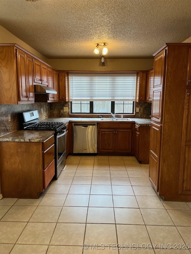 kitchen with plenty of natural light, under cabinet range hood, light tile patterned floors, and stainless steel appliances