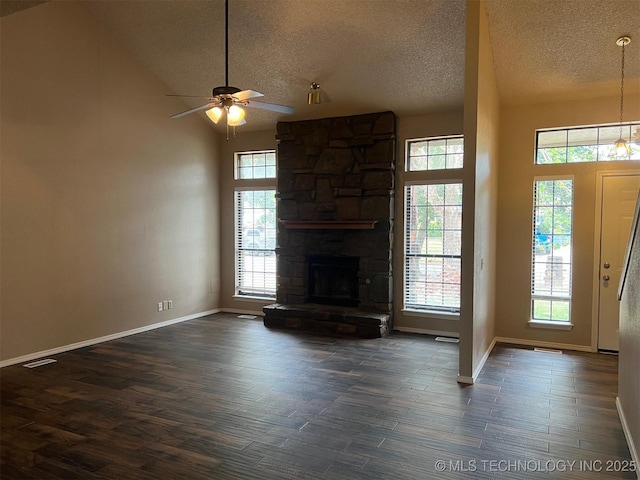 unfurnished living room with dark wood-style flooring, a textured ceiling, visible vents, a ceiling fan, and a stone fireplace