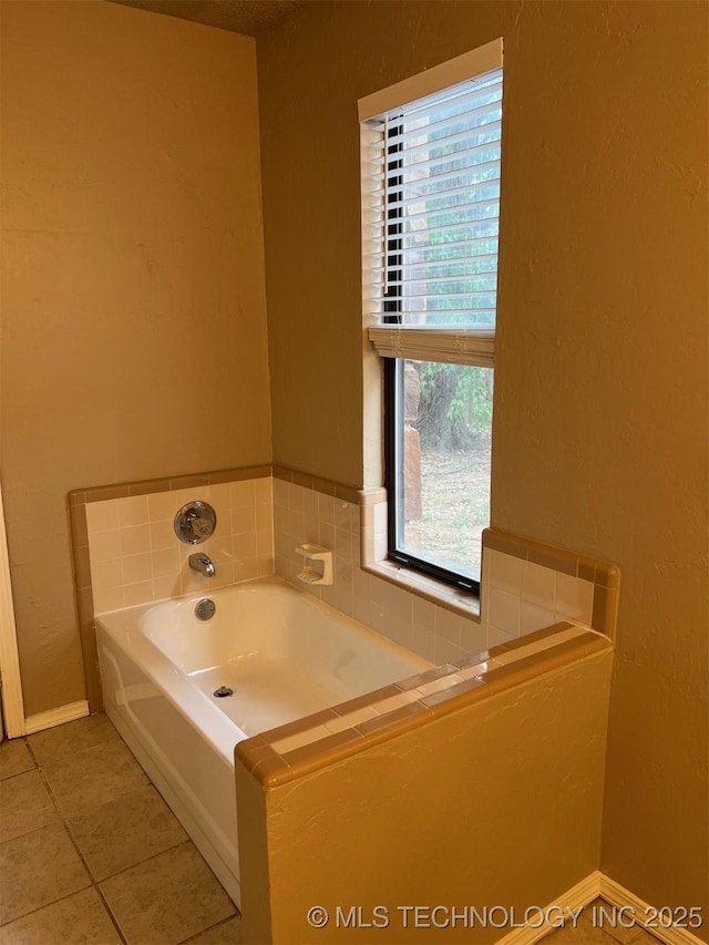 bathroom featuring tile patterned floors, baseboards, and a bath