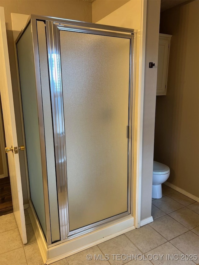 bathroom with a shower stall, tile patterned floors, and toilet