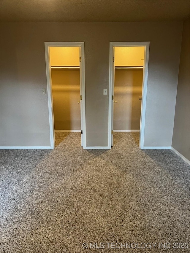 unfurnished bedroom featuring a closet, a walk in closet, and carpet