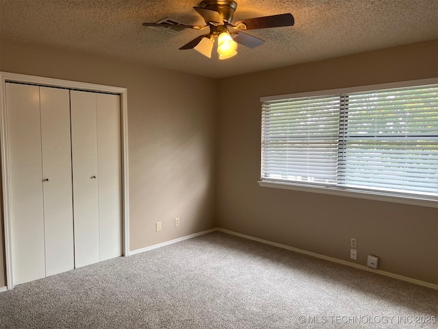 unfurnished bedroom featuring carpet flooring, baseboards, a textured ceiling, ceiling fan, and a closet