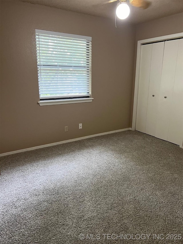 unfurnished bedroom with a textured ceiling, a closet, carpet flooring, and a ceiling fan