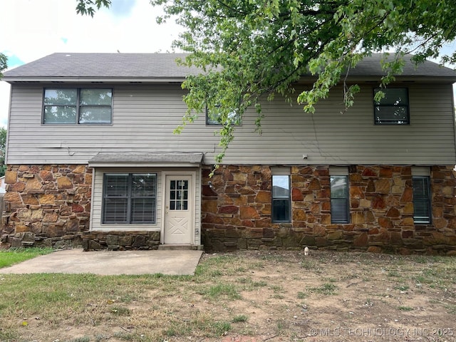 rear view of property featuring stone siding and roof with shingles