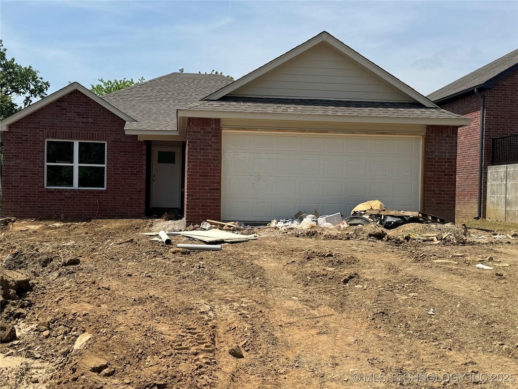 ranch-style house featuring brick siding, a shingled roof, driveway, and an attached garage