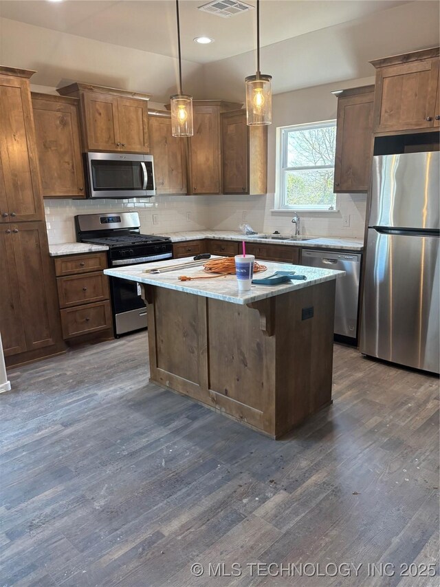 408 S Muskogee St, Sapulpa, OK 74066 - kitchen featuring appliances with stainless steel finishes, dark wood-style flooring, a center island, backsplash, and a sink